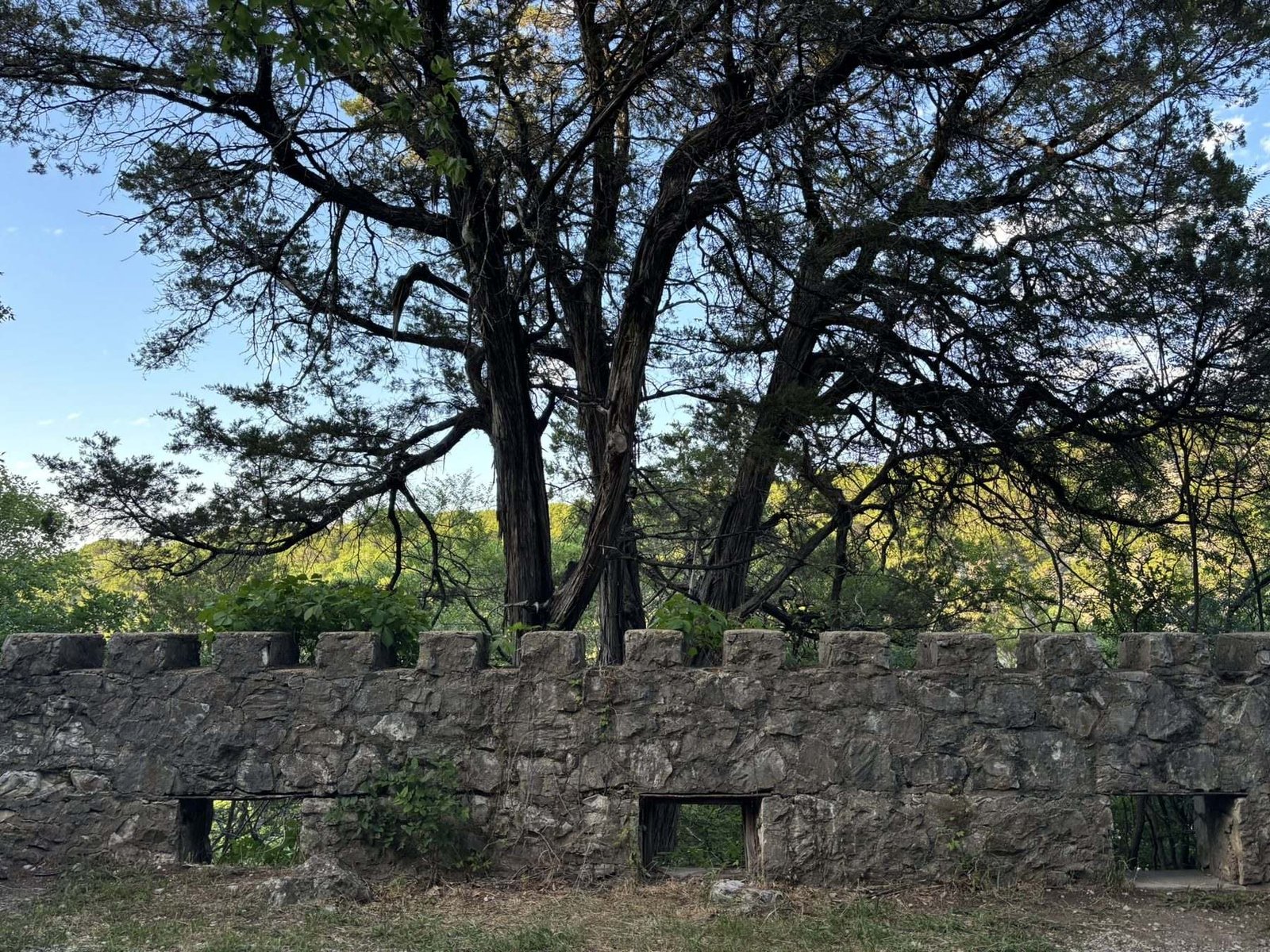 The stone ruins of Collings Castle among trees on the hillside